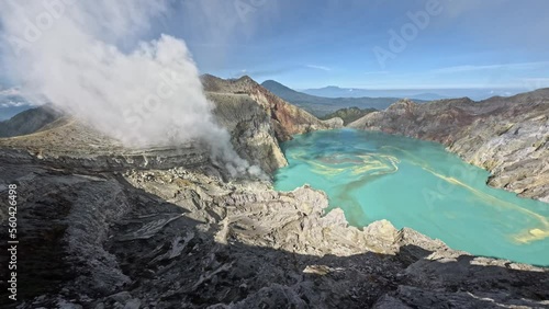 Dive to volcano crater island mountain crack stone sharp structure with acid lake turquoise blue water and miss fog aerial view. FPV sport drone shot geology formation pond cliff rocky terrain nature