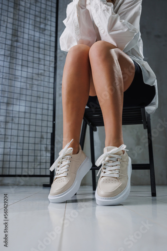 Female beautiful legs in beige casual sneakers. Women's stylish leather summer shoes