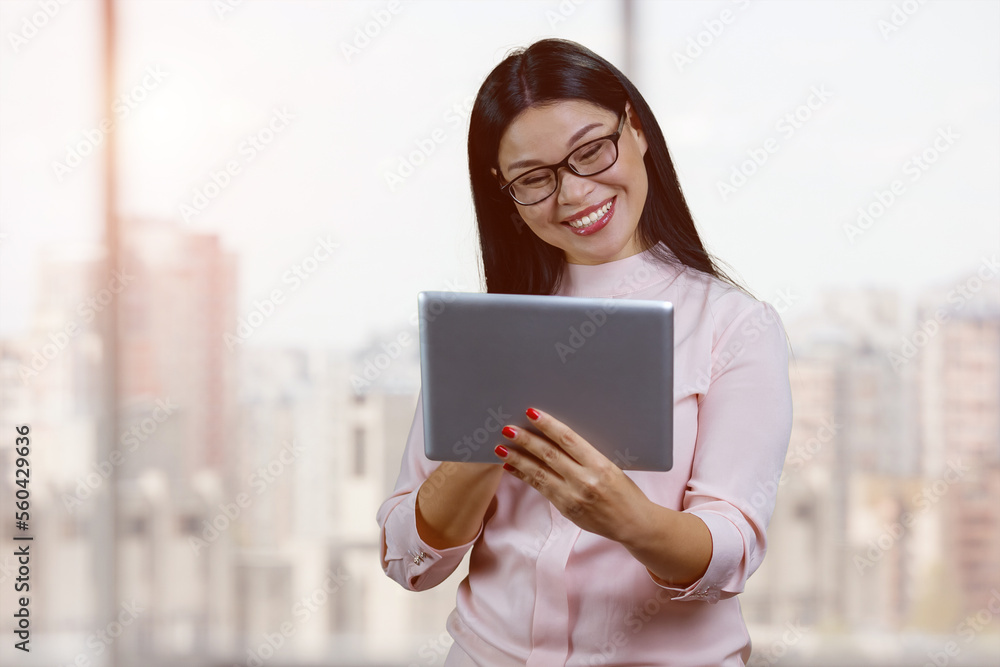 Fototapeta premium Portrait of smiling young asian businesswoman with glasses. Indoor windows bacgkground.