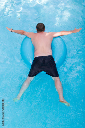 A man floats on inflatable circle, top view.