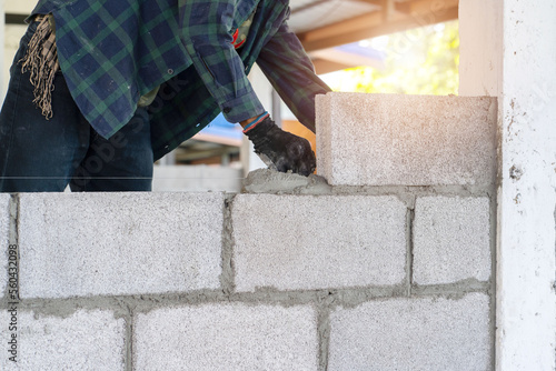 Fotótapéta masonry worker make concrete wall by cement block and plaster at construction si