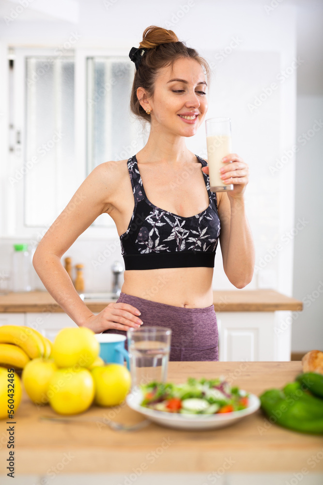 Slim girl drinking protein shake for weight loss in the kitchen