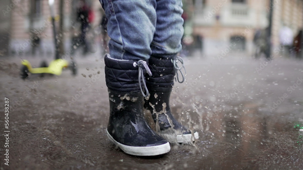 Happy child jumping into puddle of water. Joyful kid bouncing in water puddle2 Happy child jumping into puddle of water. Joyful kid bouncing in water puddle2