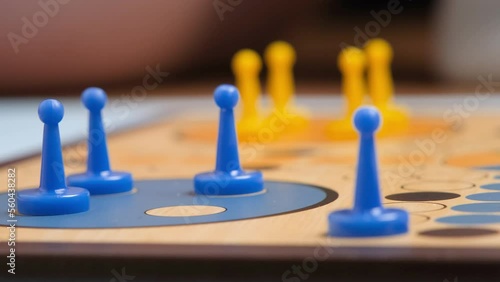 People play Ludo or Pachisi board game on beautiful wooden play board. Ludo is a strategy board game for two to four players. 4K resolution family board game video. photo