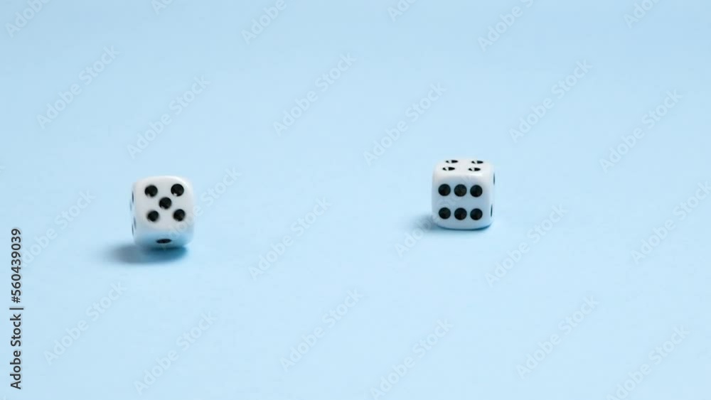 Slow motion full HD view on two dice fall on a blue background and rotate. Gambling or board games concept. Slow motion full HD view on two dice fall on a blue background and rotate. Gambling or board games concept.
