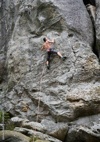 Male rock climber training rock climbing on a huge boulder