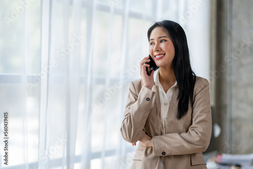 Beautiful Asian businesswoman casually talking on the phone explaining work marketing planning happy online customers in the office.