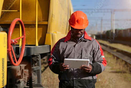 African american railway man with tablet pc at freight train terminal photo
