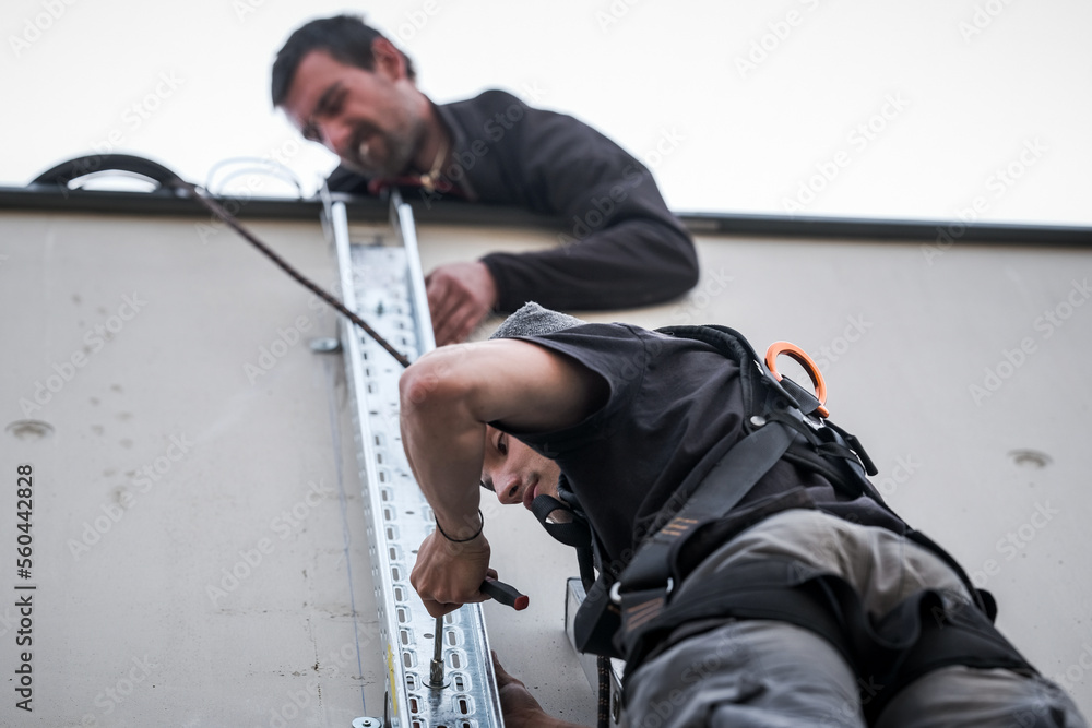 team of electrical engineers installing chutes for the supply of electricity from a solar panel installation using a wireless drill team of electrical engineers installing chutes for the supply of electricity from a solar panel installation using a wireless drill