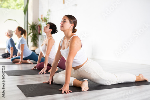 Group of active beautiful multinational women doing yoga exercise in popular sport club