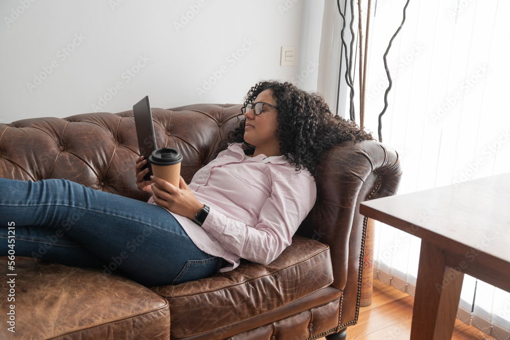 © ADDICTIVE STOCK - Woman drinking coffee and using tablet on sofa © ADDICTIVE STOCK - Woman drinking coffee and using tablet on sofa
