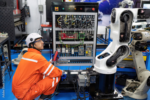 Engineer hold multimeter testing cable wiring robotic control panel at robot maintenance shop