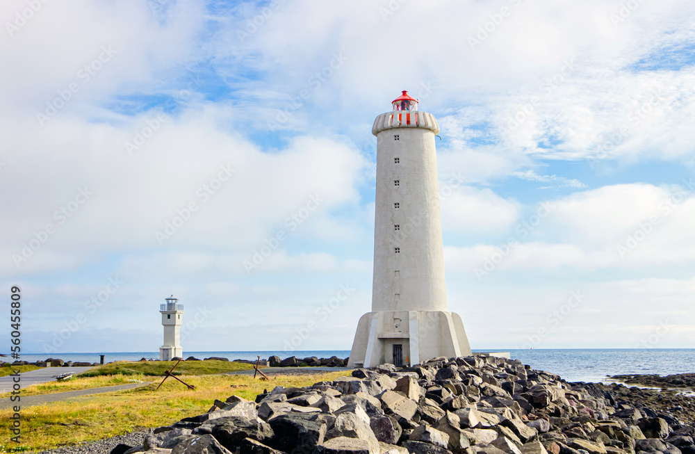 Akranes lighthouses on the west coast of Iceland. Bigger lighthouse is operational and smaller is deactivated old one. White building by the sea on sunny beautiful day.