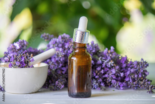 A bottle of essential oil with fresh blooming lavender twigs