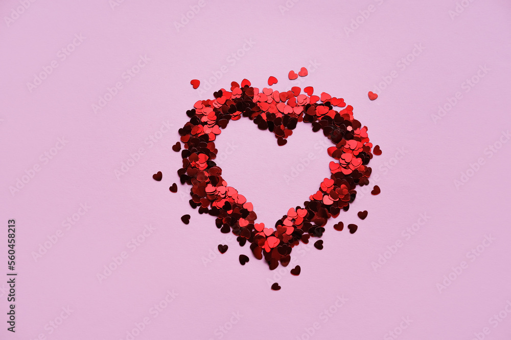 Valentine's day background. Heart made of shiny red small decorative hearts on a pink background. Flat lay, place for text.