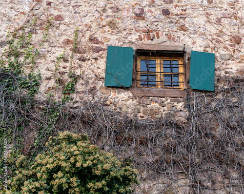 Old castle window with green shutters and old brickwork