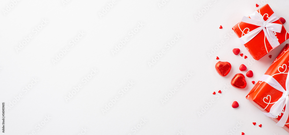 Valentine's Day concept. Top view photo of red gift boxes heart shaped chocolate candies and sprinkles on isolated white background with blank space Valentine's Day concept. Top view photo of red gift boxes heart shaped chocolate candies and sprinkles on isolated white background with blank space