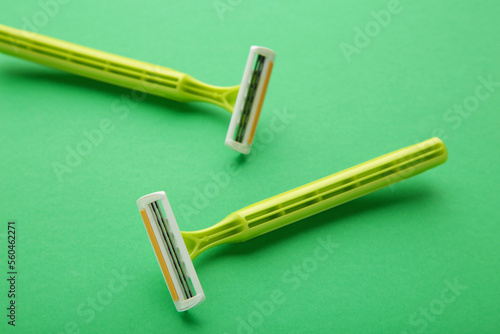 Green razors for hair removal on green background