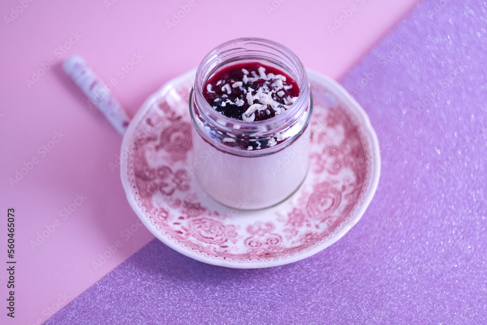 Summer dessert - delicious Italian pannacotta with coconut milk and red berries jam on a pink board