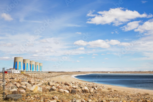 A hydroelectric station with five large concrete cylinders in a summer Saskatchewan landscape