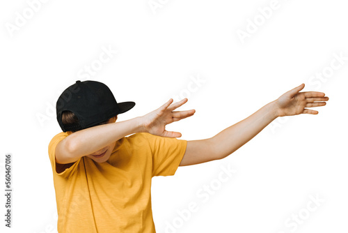 Konstfotografi Young boy dressed in yellow t-shirt and black baseball cap over transparent background makes teenagers dab gesture, moves his hands aside, covering his face, that means i did it