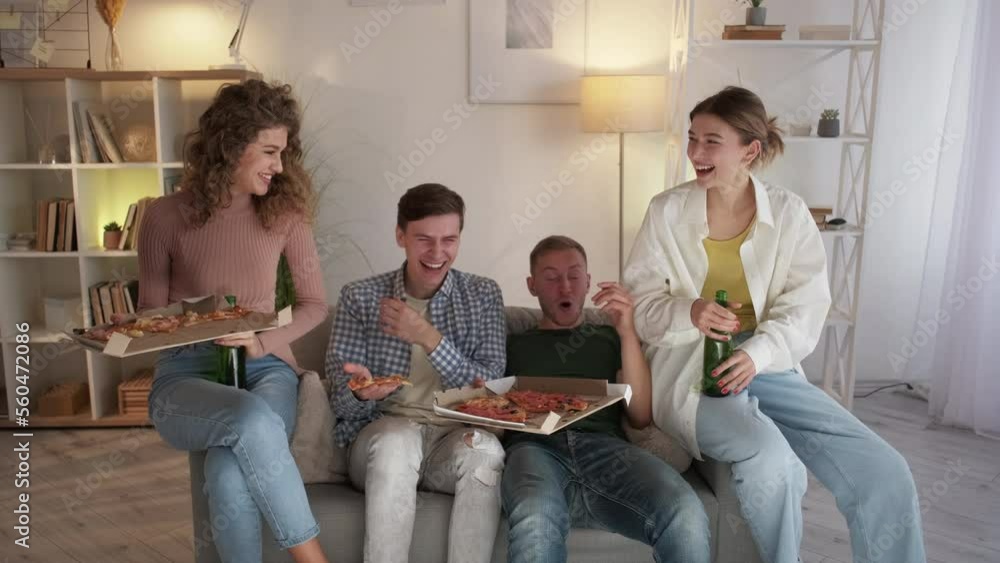 Watching sport. Competitive mood. Friends meeting. Shocked men feeling relief looking TV together with women with pizza in light home interior. Watching sport. Competitive mood. Friends meeting. Shocked men feeling relief looking TV together with women with pizza in light home interior.