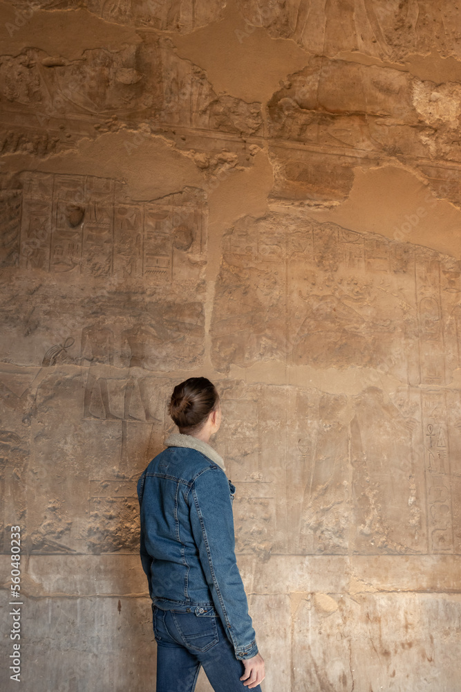 Vertical view of unrecognizable young tourist man looking the hieroglyphics art in the egyptian anciente and historical architecture