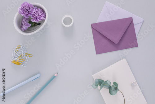 Overhead view of purple carnation flower heads, envelopes and assorted stationery on a table photo