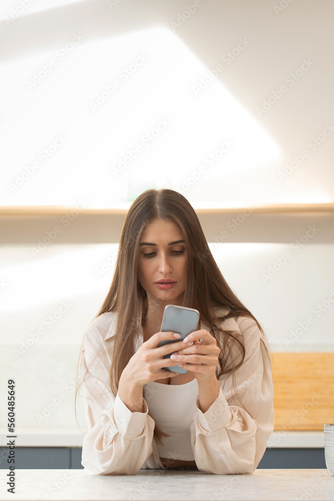 A young brunette woman uses her phone while making online purchases. Surfing the Internet A young brunette woman uses her phone while making online purchases. Surfing the Internet