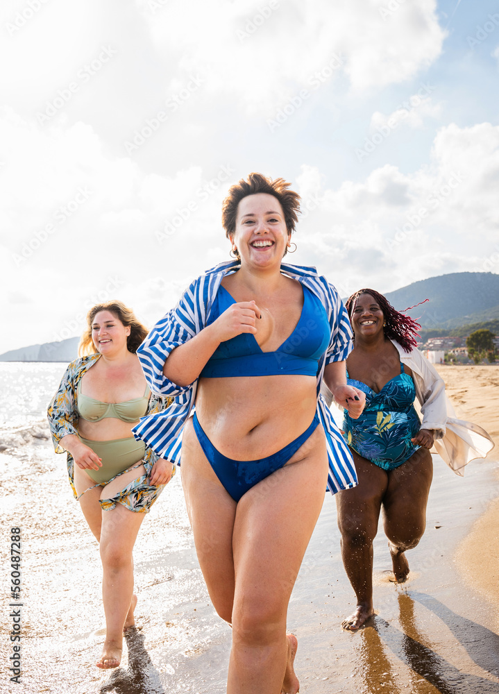 Group of beautiful plus size women with swimwear bonding and having fun at  the beach - Group