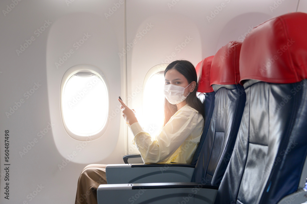 A young woman wearing face mask is traveling on airplane , New normal travel after covid-19 pandemic concept.. A young woman wearing face mask is traveling on airplane , New normal travel after covid-19 pandemic concept..