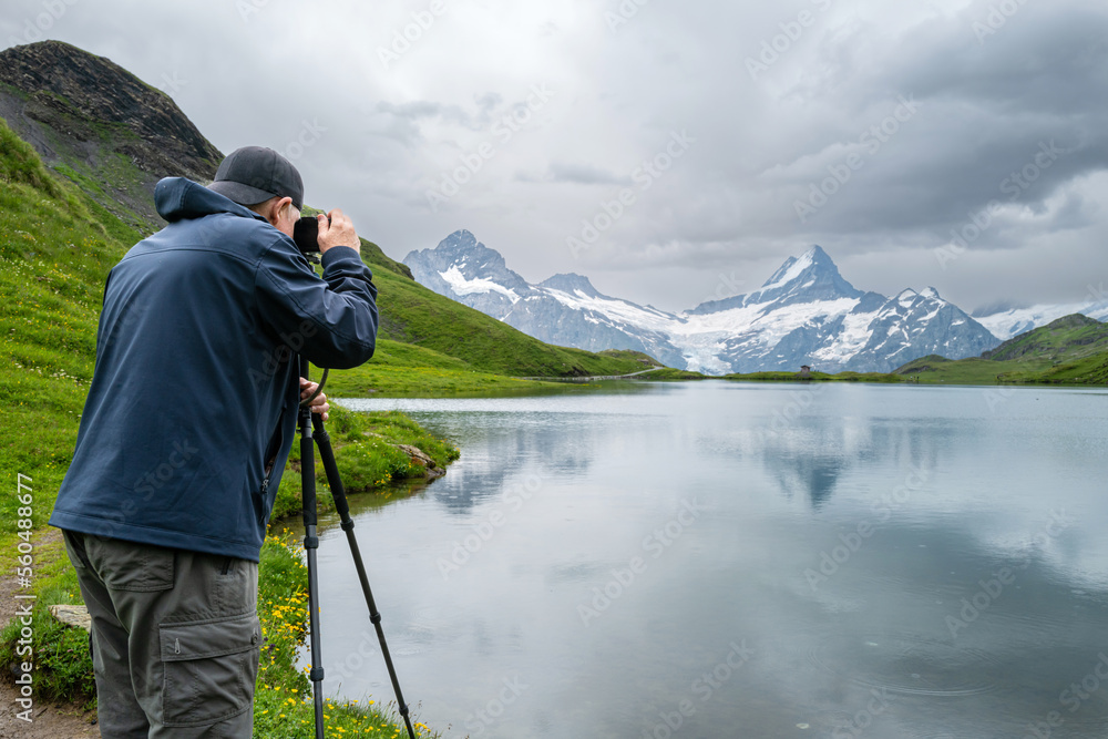 Senior man taking landscape photograph in the Swiss Alps