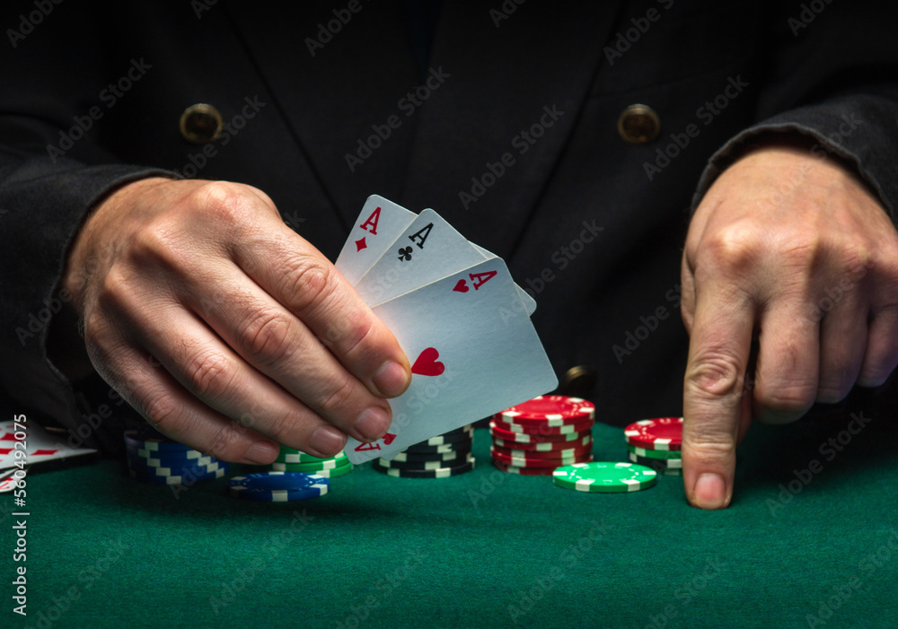 The player shows playing cards with a winning combination of three of a kind or a set in a poker game on a green table with chips in a club The player shows playing cards with a winning combination of three of a kind or a set in a poker game on a green table with chips in a club