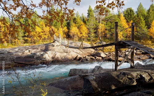 Rope bridge over the river. Autumn Finnish landscape