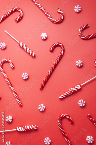 Candy canes, striped candies and lollipops on red background. Christmas or New year pattern. Vertacal card, selective focus. photo