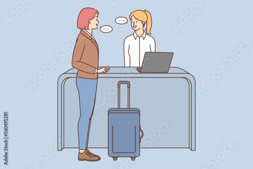 Woman with suitcase talk with administrator on reception 