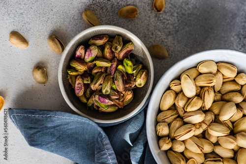 Overhead view of a bowl of pistachio nuts in shells next to a bowl of shelled pistachios photo