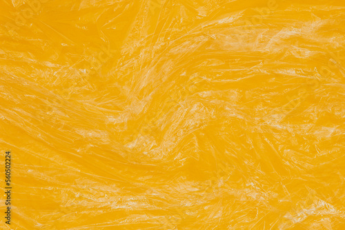 Fotografi Crumpled wrinkled plastic transparent plastic cellophane wrapper on yellow color background