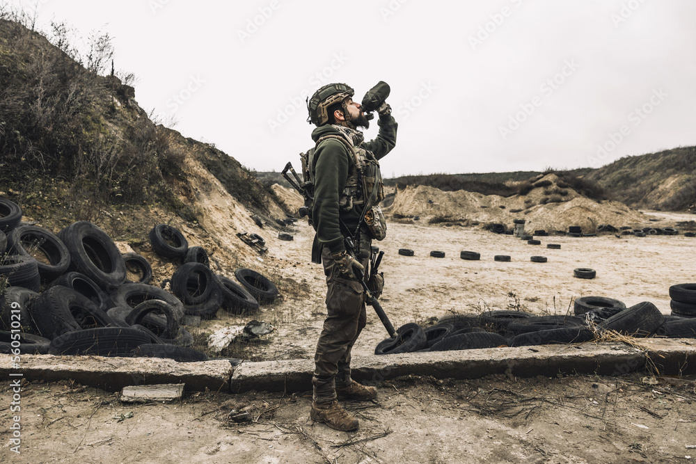 Fototapeta premium Soldier in military uniform drinking from flask