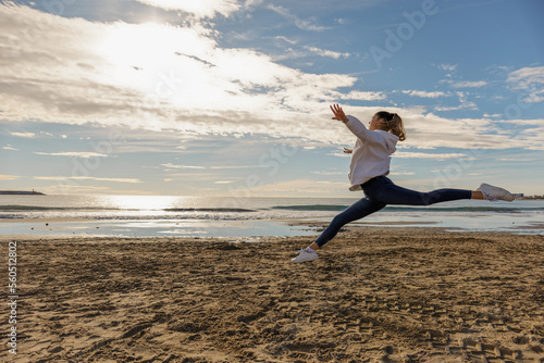 A beautiful energetic young woman doing gymnastics on beach