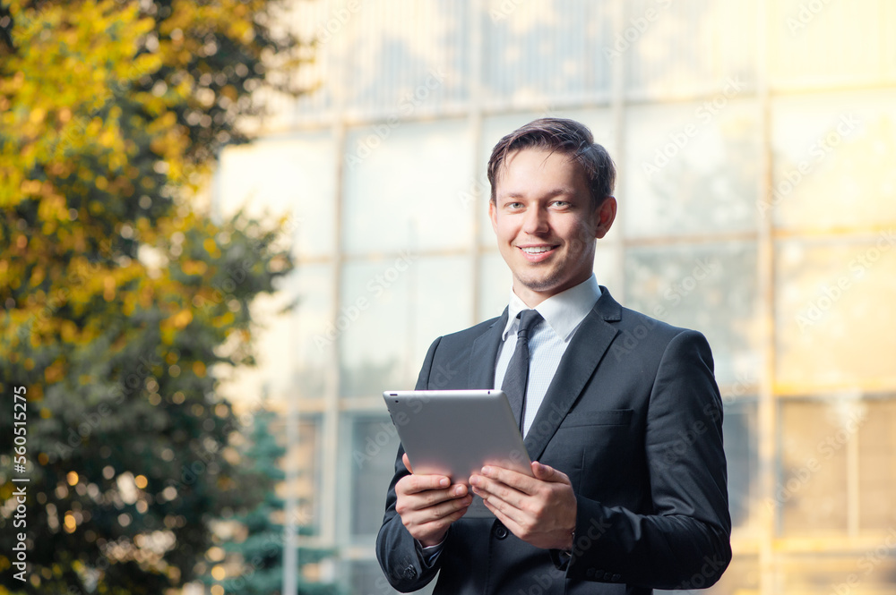 Businessman with digital tablet. Confident young man in suit and tie using digital tablet and smiling at camera while standing outdoors Businessman with digital tablet. Confident young man in suit and tie using digital tablet and smiling at camera while standing outdoors