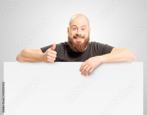 Confident at success. Happy bearded man showing thumb up and leaning at copy space while standing against grey background