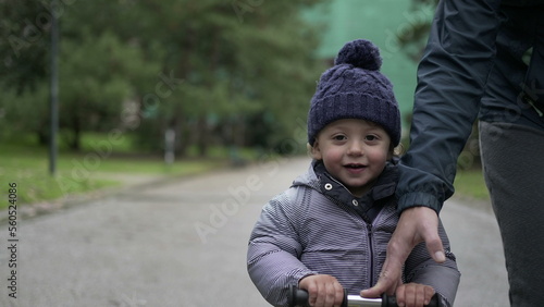 Toddler boy rides scooter outside at park. Baby child riding scooter2