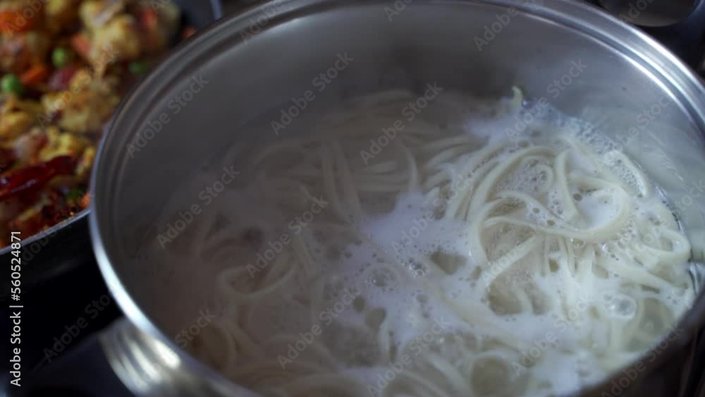 Spaghetti noodles being boiled in a hot water inside a stainless steel bowl , Italian food preparation Spaghetti noodles being boiled in a hot water inside a stainless steel bowl , Italian food preparation