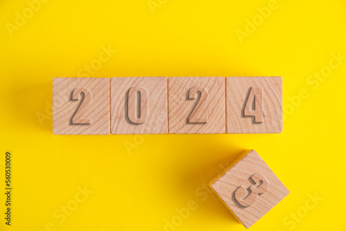 Wooden cubes with numbers 2023 yellow background turning into 2024. photo