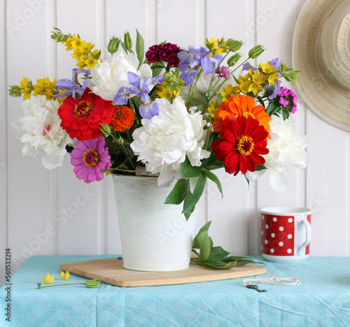 summer rustic still life with a bouquet of garden flowers. peonies, zinnias, irises and carnations.