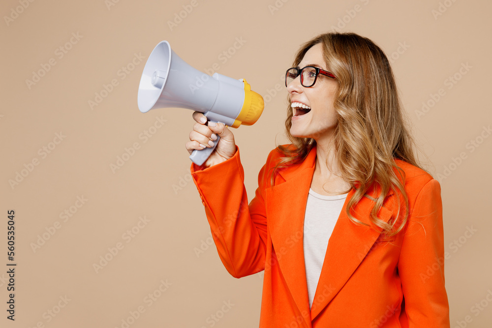 Young employee business woman corporate lawyer wear classic formal orange suit glasses work in office hold scream aside megaphone announces discounts sale Hurry up isolated on plain beige background. - obrazy, fototapety, plakaty 