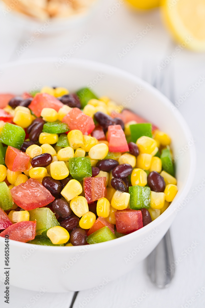 Mexican style colorful fresh vegetable salad made of beans, corn, tomato and green bell pepper served in white bowl, photographed on white wood (Selective Focus, Focus one third into the salad) Mexican style colorful fresh vegetable salad made of beans, corn, tomato and green bell pepper served in white bowl, photographed on white wood (Selective Focus, Focus one third into the salad)