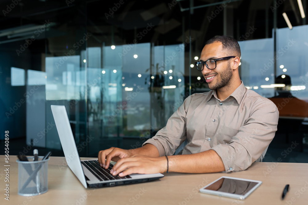 Young successful Indian programmer working inside modern development company, man using laptop to write code for software. Young successful Indian programmer working inside modern development company, man using laptop to write code for software.