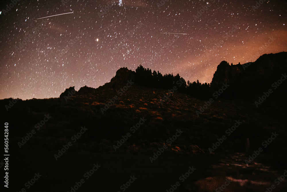 Mountains at night and stars in the sky, the big bear, falling stars and planets in the sky. Noisy photo at long exposure